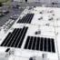 Aerial view of rooftop solar arrays and installers at Restoration Management Company in Hayward
